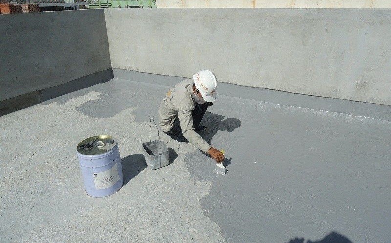 Vữa chống thấm xi măng polymer được quét lên bề mặt sàn, chuẩn bị cho quá trình thi công